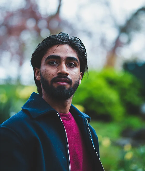 Anmol in a navy jacket, moody park portrait