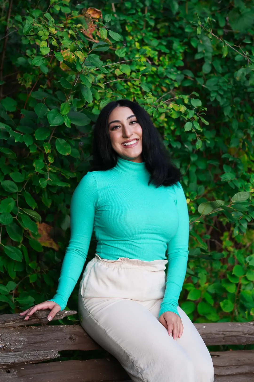 Sarah in a turquoise top against green ivy